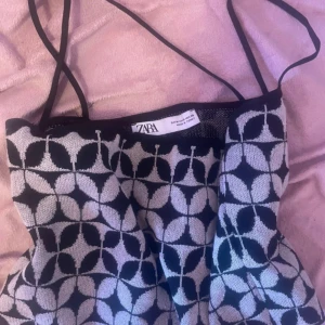 Mönstrad tubtopp från Zara - Säljer en snygg tubtopp från Zara med svart och vit geometriskt mönster. Toppen har tunna axelband och är perfekt för att skapa en trendig look. Passar till både jeans och kjol.