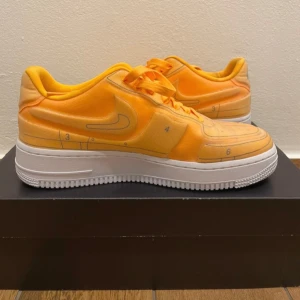 Nike Air Force 1 '07 LX Laser Orange - Nike Air Force 1 '07 LX i en riktigt snygg laser orange färg. Skorna har en unik design med tunna svarta linjer och detaljer som ger en cool 3D-effekt. Klassisk vit sula och orange snörning. Perfekta för dig som vill sticka ut med dina sneakers.