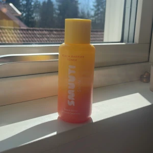 Peach Barrier Toner från Smuti Skin - Fräsch toner med persikoextrakt från Smuti Skin. Flaskan är gul och orange med vitt tryck och har en praktisk skruvkork. Perfekt för att återfukta och balansera huden i din hudvårdsrutin.