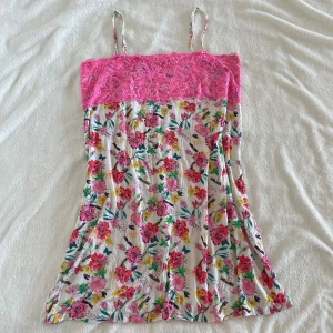 Blommig kortklänning med spets från Hunkemöller - Söt nattlinne/klänning med smala axelband från Hunkemöller. Överdelen är i rosa spets och resten av nattlinnet har ett färgglatt blommigt mönster på vit botten. Perfekt för varma dagar eller som nattlinne.