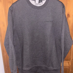 Grå sweatshirt från J.Lindeberg - Säljer en stilren grå sweatshirt från J.Lindeberg med diskret broderad logga på bröstet. Tröjan har rund halsringning och långa ärmar. Perfekt för en avslappnad och snygg look. Sweatshirten är oanvänd, köpt för 1100