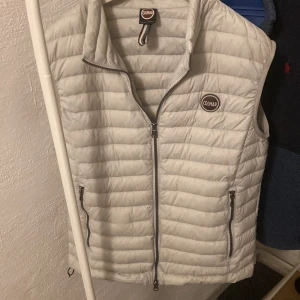 Colmar väst - Säljer en vit dunväst från Colmar med quiltad design och dragkedja framtill. Västen har två fickor med dragkedja och en hög krage. Perfekt för lager-på-lager och enkel att matcha med olika outfits.