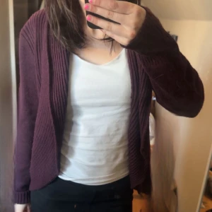 Vinröd kofta i ribbat material - Säljer en vinröd kofta med öppen front och ribbat material. Koftan har långa ärmar och en avslappnad passform, perfekt att slänga över en t-shirt eller linne.