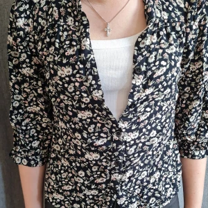 Svart blommig blus från Happy Holly - Säljer en svart blus från Happy Holly med små vita och ljusrosa blommor. Blusen har trekvartsärm och knappar framtill. Perfekt för dig som gillar romantisk stil och vill ha något lätt och luftigt. Den är inte använd och är i storlek 32/34