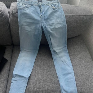 Ljusblå skinny jeans - Säljer ett par ljusblå skinny jeans med klassisk femficksdesign och normalhög midja. Jeansen har dragkedjegylf och smal passform hela vägen ner. Perfekta för dig som gillar en enkel och stilren look.