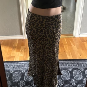 Leopardmönstrad långkjol - Säljer en snygg långkjol med leopardmönster. Kjolen har en rak passform och är i ett mjukt, följsamt material som ger en cool look. Perfekt för dig som vill sticka ut lite extra.