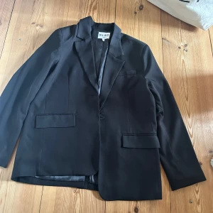 Oversized svart kavaj  - En perfekt kavaj att dra på sig över outfiten om det blir lite kalt på kvällen. Den är i mycket bra skick bara använd två gånger. I storleken är den stor då det är designen på kavajen. 