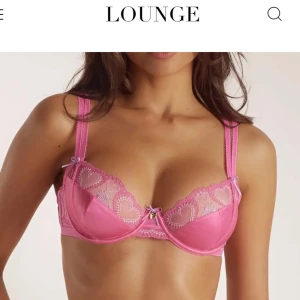 Oanvänd rosa spets-bh från Lounge🫶🏽💗 - Säljer en superfin rosa bh från Lounge med hjärtformade spetsdetaljer och satinpartier.🤩 Bh:n har dubbla axelband, liten rosett framtill och ett litet guldfärgat hjärthänge. Perfekt för dig som gillar romantiska detaljer! Säljer då jag köpte en storlek för liten men klippte av lappen☺️💞