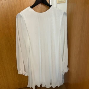 Studentklänning / vit klänning  - Vit klänning, lite plisserad. Perfekt studentklänning helt ny med prislappen kvar! Slutsåld och väldigt populär. 