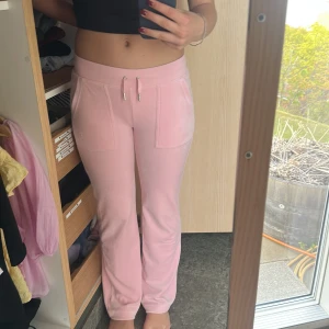 Rosa mjukisbyxor från Juicy Couture - Säljer ett par ljusrosa mjukisbyxor från Juicy Couture i storlek XS. Byxorna har raka ben, dragsko i midjan och fickor både fram och bak med snygga detaljer. Perfekta för en avslappnad och trendig look. Passar även S. Är en och 178 och passar. Og pris 1200kr. Pris kan diskuteras!