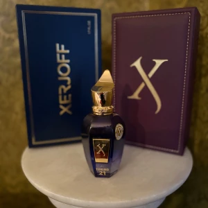 Xerjoff Torino 21 Eau de Parfum  - Lyxig parfymflaska i djupblått glas med gulddetaljer och elegant guldlock. Kommer i exklusiv lila ask med X-logga i guld. Doften är en del av Xerjoffs kollektion och utstrålar exklusivitet och stil. NÄSTAN HELT FULL