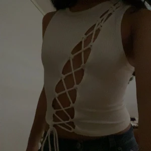 Vit croppad linnetopp med snörning - Säljer en vit croppad linnetopp med unik snörningsdetalj framtill. Toppen är ärmlös och har en tight passform som framhäver figuren. Perfekt för dig som vill ha tops för att festa och se snygg ut med 💗💗Toppen är xxs men passar mig även som är xs ✌🏽Säljer för 35 vid direkt köp 💗