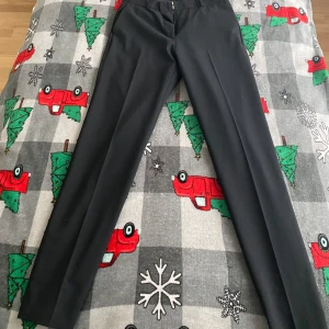 Svarta kostymbyxor från STOCKH LM - Säljer ett par svarta kostymbyxor från STOCKH LM i en klassisk rak modell. Byxorna har tryckveck framtill och stängs med dragkedja och knapp. Perfekta för en snygg look och passar till många olika tillfällen. Byxorna har en reva nedtill som kan lagas.