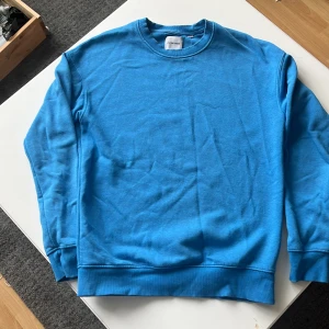 Blå sweatshirt från Jack & Jones - En enkel och stilren blå sweatshirt från Jack & Jones. Tröjan har rund halsringning, långa ärmar och ribbade muddar vid ärmslut och nederkant. Perfekt för en avslappnad och bekväm stil.