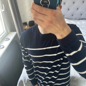 Mörkblå randig tröja från Dressmann - Säljer en mörkblå tröja från Dressmann med vita horisontella ränder. Tröjan har rund halsringning och långa ärmar. Perfekt för en stilren och klassisk look. Materialet känns mjukt och bekvämt.