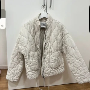 Beige quiltad jacka från ZARA - Säljer en beige quiltad jacka från ZARA med dragkedja framtill och två stora fickor. DRAGKEDJAN ÄR SÖNDER SÅ MAN KAN INTE STÄNGA JACKAN
