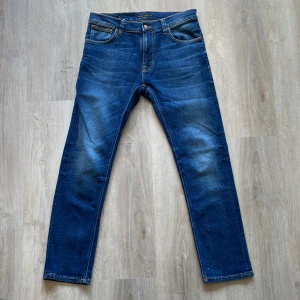Blå jeans från Nudie Jeans - (HELT NYA)Säljer ett par klassiska blå jeans från Nudie Jeans med raka ben och fem fickor. Jeansen har knappgylf och diskret broderad bakficka. Perfekta för dig som gillar stilrena och tidlösa jeans. Dem är även en väldigt stilren tvätt som får dem att sticka ut på ett snyggt sätt.  Har ni frågor om jeansen så är det bara att fråga på. ( helt nya lapparna sitter bara inte på) pris ej hugget i sten. 