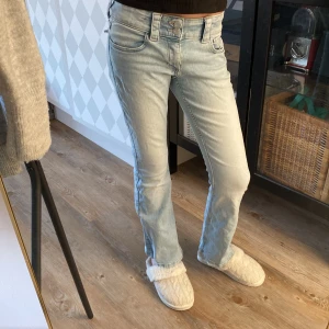 Ljusblå jeansbyxor från H&M - Ljusblå jeansbyxor med utsvängda ben och dubbla knappar i midjan. Klassisk femficksmodell med snygga detaljer på bakfickorna. 