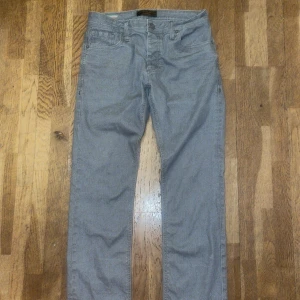 Grå jeans från Jack & Jones - Säljer ett par regular fit jeans från Jack & Jones med en bra passform. Dessa är mellan slim och baggy vilket gör att dom inte är för loose och för tighta. Köpte dom här från Plick men de var för små för mig, därför ej använda bara testade. Ej mina bilder, bilder från han jag köpte byxorna av.