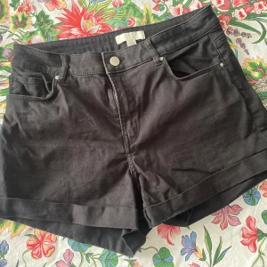 Svarta shorts från H&M - Snygga svarta shorts från H&M i en klassisk design. De har en dragkedja och knapp framtill samt fickor både fram och bak. Perfekta för en stilren look.