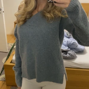 Blå stickad tröja - Mysig blå stickad tröja med v-ringning och långa ärmar. Perfekt för kyligare dagar och ger en avslappnad look. Passar bra till både jeans och kjol.