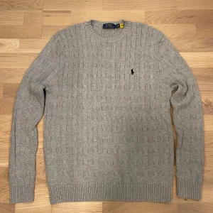 Grå kabelstickad tröja från Ralph Lauren - Säljer en stilren grå kabelstickad tröja från ralph Lauren, 10/10 skick som passar till allt. Tröjan är i storlek S och kommer till 100% ge dig massor av komplimanger. 