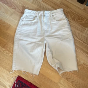 Beige shorts med fransar - Säljer ett par snygga beige shorts med fransar i kanten. De har en klassisk femficksdesign och är perfekta för en avslappnad stil. Passar bra till varma dagar och ger en cool look.