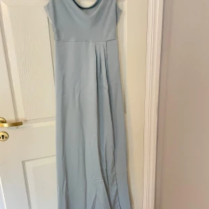 Ljusblå/grön långklänning från Bubbleroom - Elegant långklänning från Bubbleroom med en stilren design. Klänningen har korta ärmar och en dragkedja i ryggen för enkel påklädning. Perfekt för speciella tillfällen.Inga tecken på användning   Använd endast en gång Med slits Köptes för 1000kr