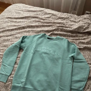 Turkos tröja från Peak Performance - Säljer en snygg turkos tröja från Peak Performance. Tröjan har långa ärmar och ett stilrent tryck på bröstet. Perfekt för en avslappnad stil. Hör av dig vid intresse!