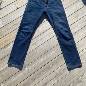 Levis 505 jeans i mörkblå denim - Säljer ett par klassiska Levis 505 jeans i mörkblå denim. De har en rak passform och är tillverkade i slitstarkt jeansmaterial. Perfekta för en avslappnad stil. W33(sitter som W32)/ L32