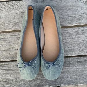 Blå ballerinaskor från H&M - Snygga blå ballerinaskor från H&M med en söt rosett på ovansidan. Skorna är tillverkade i ett jeansliknande material och har en bekväm passform. Perfekta för en avslappnad stil.