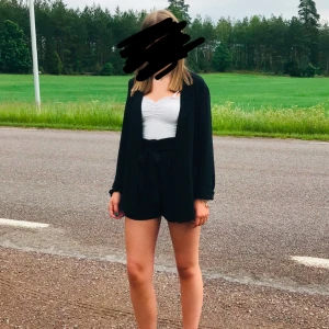 Svarta kostymshorts med knytband - Snygga svarta shorts med hög midja och knytband i midjan. Perfekta för en stilren look. De har en lös passform och är tillverkade i ett mjukt material.