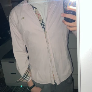 Ljusrosa skjorta från Burberry - Säljer en stilren ljusrosa skjorta från Burberry med klassiskt rutigt mönster på insidan, perfekt för en elegant look och perfekt för sommaren. Säljer pga att den är lite tajt på mig. Hör av dig om du har några frågor 😊
