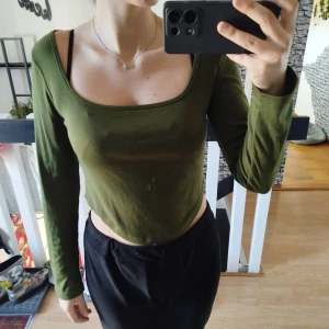 Olivgrön croppad topp - Står storlek xxl men är snarare L. Snygg olivgrön croppad topp med långa ärmar och en bred, fyrkantig urringning. Perfekt för en trendig och avslappnad stil.