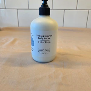 Sicilian Sunrise Body Lotion - Fräsch body lotion med doft av nyplockade citroner och solvärmt trä. Flaskan rymmer 350 ml och har en praktisk pump för enkel användning. Perfekt för att återfukta huden och ge en uppfriskande känsla. Använd ett pumptryck