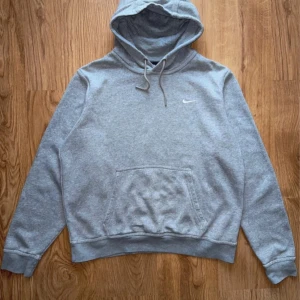 Grå Nike y2k hoodie🔥 - Säljer en klassisk grå hoodie från Nike med en liten vit logga på bröstet. Tröjan har en stor ficka framtill och justerbar huva med snören. Perfekt för en avslappnad stil. Pris kan diskuteras!