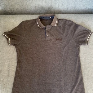 Brun pikétröja, Hugo BOSS - Säljer en stilren brun pikétröja från Hugo BOSS den är i storleken S, färgen på bilden är lite konstig men det är pågrund av dåligt ljus. Hör av er om ni är intresserade, Pris kan alltid diskuteras!