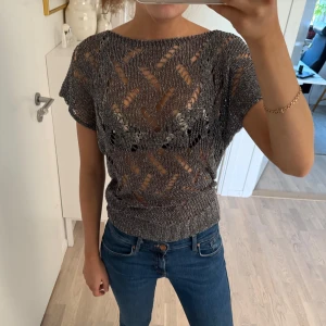 Grå/silvrig stickad topp - Säljer en snygg grå stickad topp med korta ärmar och ett genombrutet mönster💓💓 står ingen storlek men passar XS-M🤗