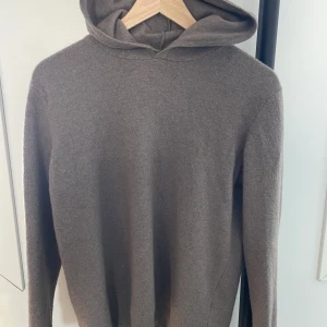 Grå hoodie från Oscar Jacobson - Säljer en stilren grå hoodie från Oscar Jacobson, tillverkad i Italien. Tröjan har en klassisk design med huva och långa ärmar, perfekt för en avslappnad look. Passar bra till både jeans och chinos. Sitter som en S.