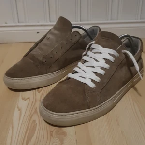 Vagabond paul 2.0  - Snygga bruna sneakers från Vagabond i mocka med vita snören. Skorna har en stilren design och är perfekta för en avslappnad look. Yttersulan är tillverkad av syntetmaterial och insidan har en kombination av läder och textil. Ny pris 1500kr och båda kommer med sko snören på hade bara inget på bilden. Kan också ta byten