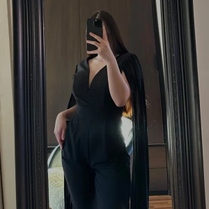 Jumpsuit klänning  - Elegant svart långklänning med långa plisserade ärmar och v-ringning. Perfekt för en stilren look med en touch av dramatik. Klänningen har en smickrande passform och är tillverkad i ett mjukt material.🥰🥰🥰