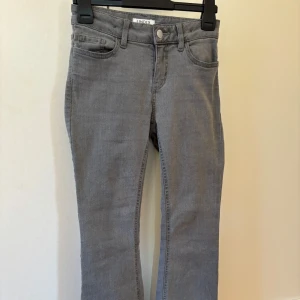 Grå jeansbyxor från Lindex - Snygga grå jeansbyxor från Lindex med klassisk femficksdesign. Byxorna har en flare passform och är perfekta för en stilren look. De är tillverkade i ett bekvämt material som ger en skön känsla hela dagen.