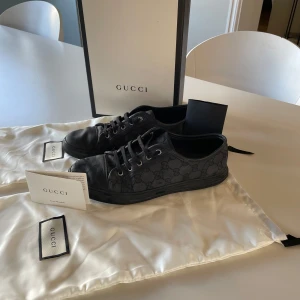 Svarta sneakers från Gucci - Snygga svarta sneakers från Gucci med det ikoniska monogrammönstret. Skorna har snörning och en diskret design som passar perfekt för en stilren look. Levereras med originalförpackning, 2xdustbag ock kvitto medföljer! Kan tänka mig byta mot andra skor!