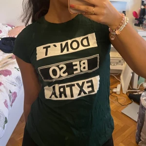 Mörkgrön t-shirt med text - Snygg mörkgrön t-shirt med texten 'DON'T BE SO EXTRA' i vitt och svart. Perfekt för en avslappnad stil med en touch av humor. Kortärmad och bekväm passform.