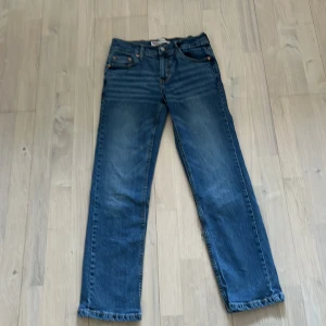 Blå jeans från Levi's - Säljer ett par klassiska blå jeans från Levi's med rak passform. De har en knappgylf och femficksdesign. Perfekta för en avslappnad stil.