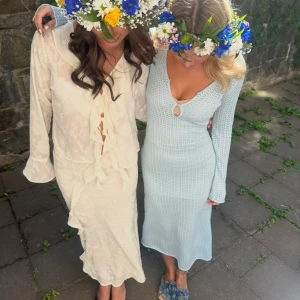 Ljusblå stickad långklänning - Snygg ljusblå stickad långklänning med v-ringning och två dekorativa öppningar framtill. Perfekt för en stilren look med långa ärmar och en figurnära passform.
