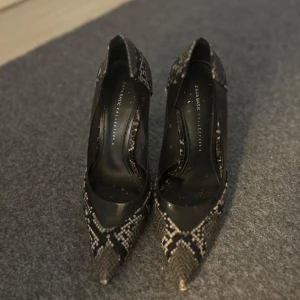 Ormskinnsmönstrade klackar från Zara - Snygga klackar med ormskinnsmönster från Zara. Skorna har en spetsig tå och hög klack, vilket ger en elegant look. Perfekta för att lyfta vilken outfit som helst.