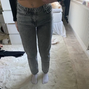 Grå jeans - Snygga grå jeans med hög midja och en klassisk femficksdesign. De har en straight passform och är perfekta för en avslappnad stil. Jeansen har en dragkedja och knapp framtill.