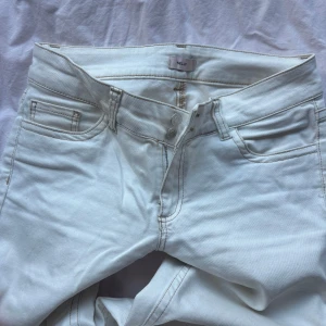 Vita jeansbyxor från NLY - Säljer ett par vita jeansbyxor från NLY med klassisk femficksdesign och raka ben. Byxorna har hög midja och stängs med dragkedja och knapp. Perfekta för en fräsch och stilren look.