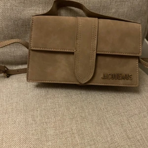 Beige axelväska i mocka - Säljer denna fina axelremsväskan som tyvärr aldrig kom till användning, köpt här på plick, priset är inte skrivet i sten